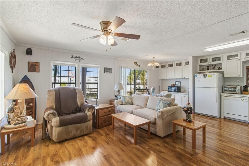Living area with light wood-type flooring, a textured ceiling, ceiling fan, and a chandelier