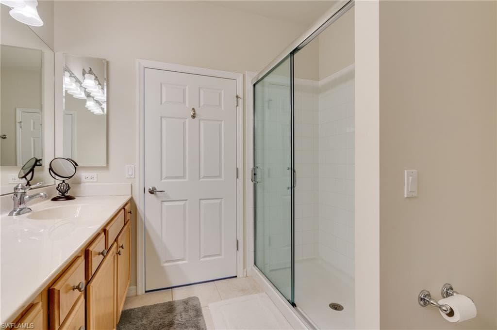Full bathroom with vanity, light tile patterned floors, and a shower stall