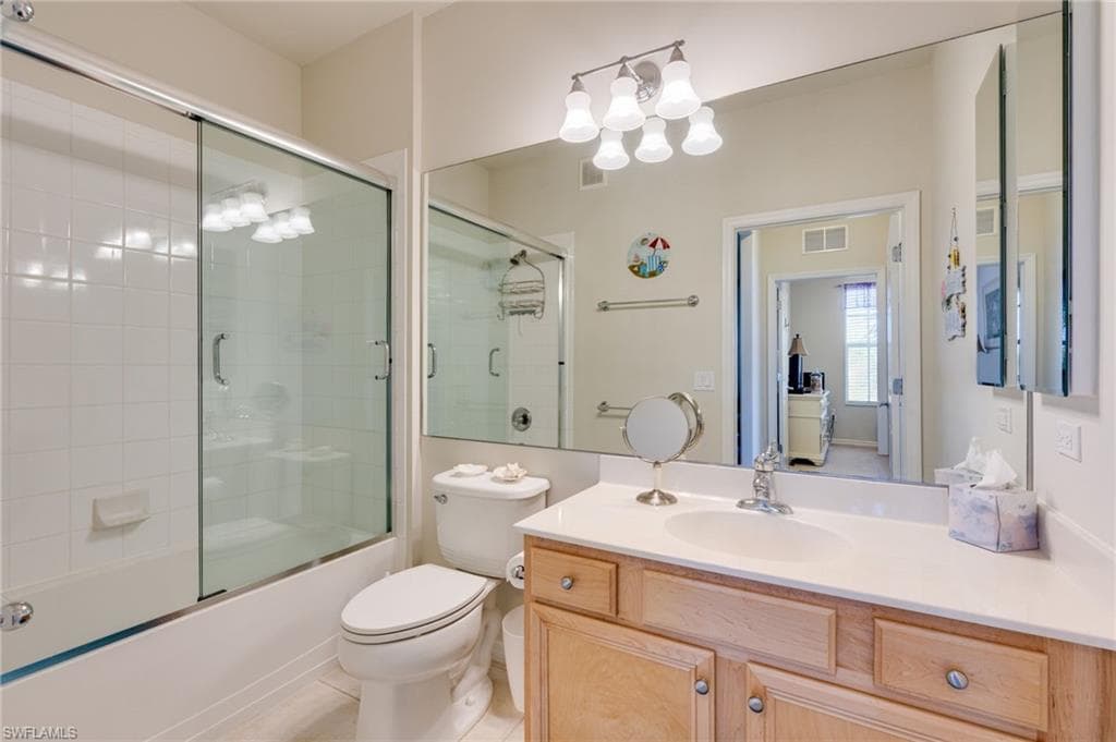 Bathroom with vanity, combined bath / shower with glass door, light tile patterned floors, and a chandelier