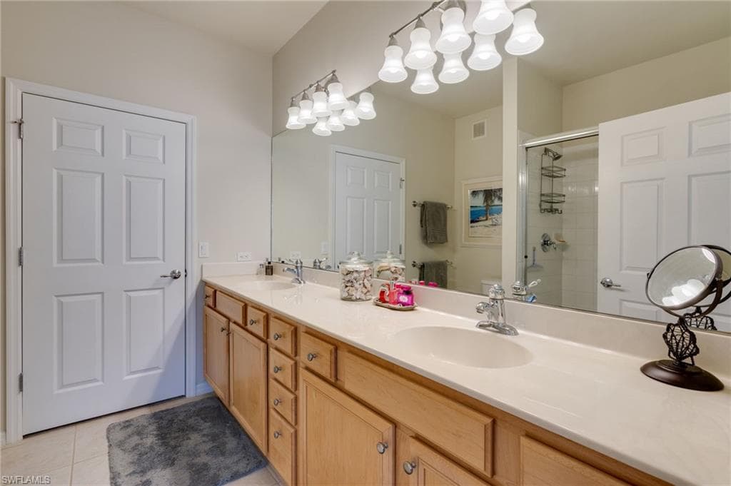Bathroom with double vanity, a stall shower, and light tile patterned floors