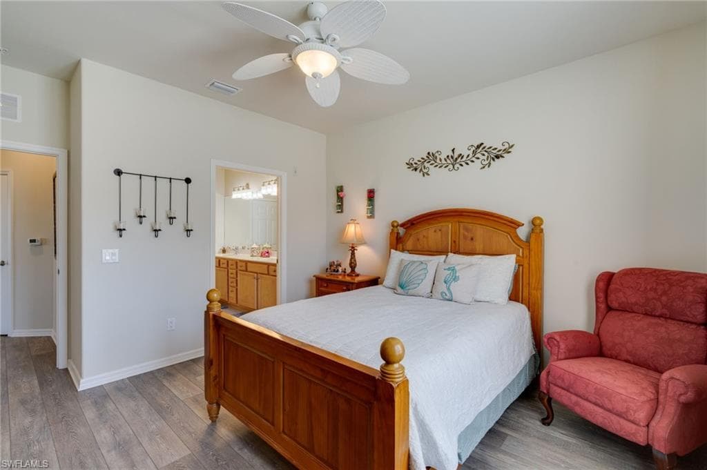 Bedroom featuring wood finished floors, a ceiling fan, and ensuite bathroom