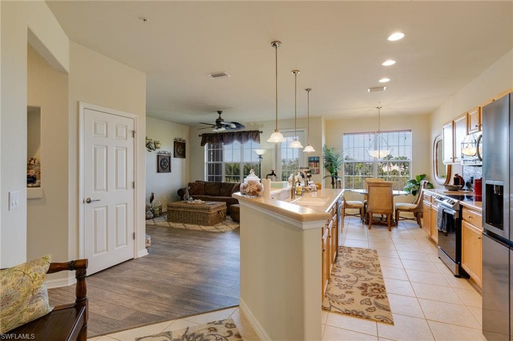 Kitchen with pendant lighting, light countertops, appliances with stainless steel finishes, open floor plan, and light tile patterned floors