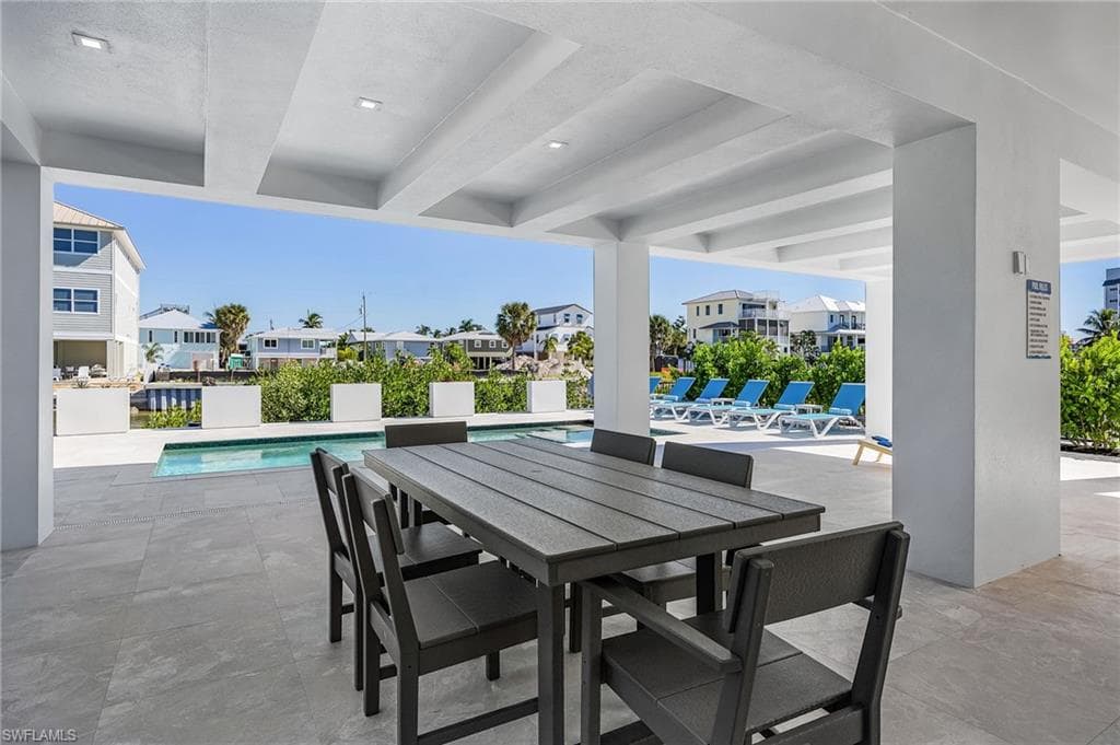 View of patio with a community pool, a residential view, and outdoor dining area - Virtually Edited Image