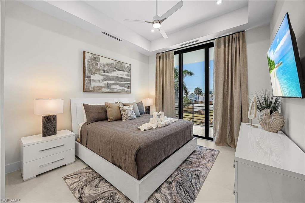 Bedroom featuring access to exterior, a ceiling fan, a raised ceiling, and recessed lighting - Virtually Edited Image