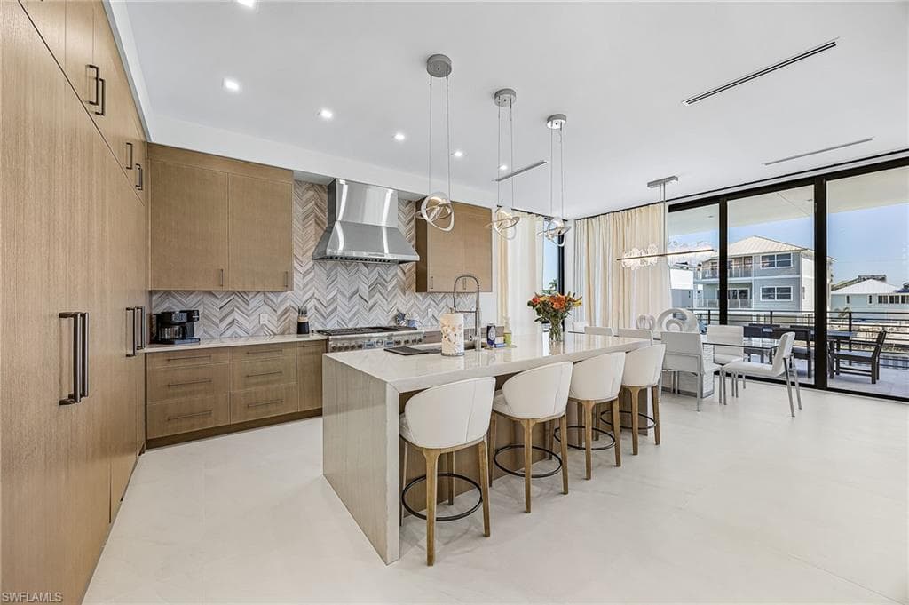 Kitchen with modern cabinets, light stone counters, decorative light fixtures, decorative backsplash, and floor to ceiling windows - Virtually Edited Image