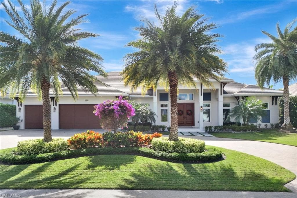 View of front of home featuring driveway, a front lawn, a tile roof, stucco siding, and a garage