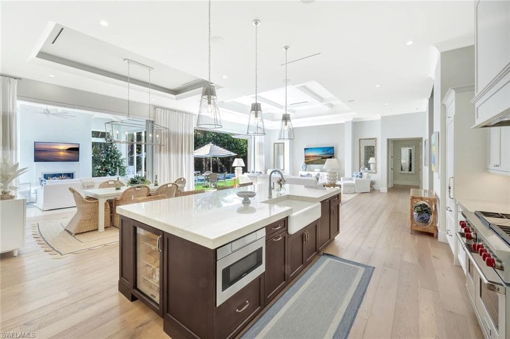 Kitchen with open floor plan, dark brown cabinets, appliances with stainless steel finishes, hanging light fixtures, and recessed lighting