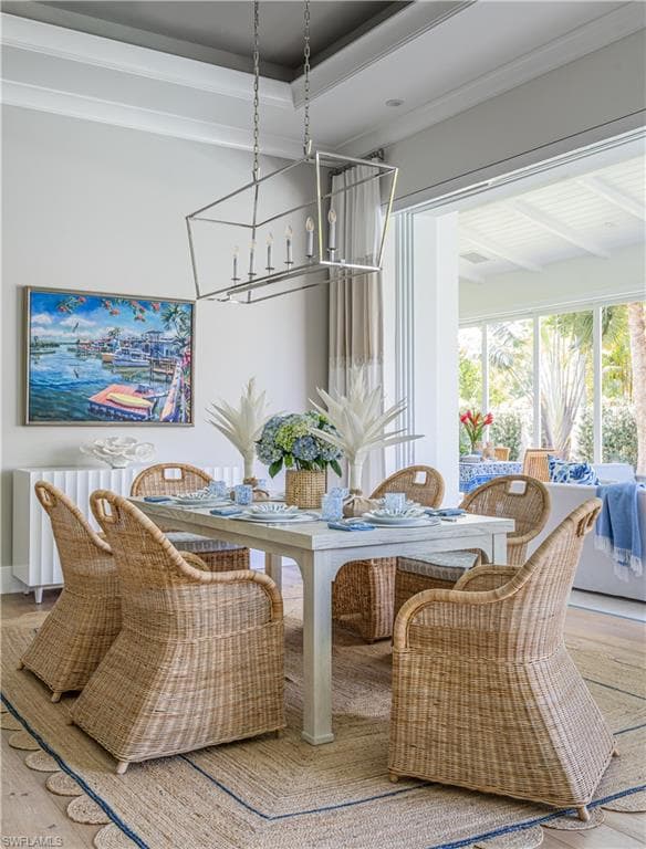 Dining area featuring wood-type flooring, crown molding, and a chandelier