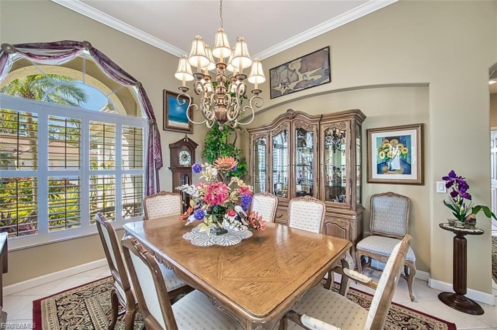 Dining room with healthy amount of natural light, ornamental molding, a chandelier, and light tile patterned floors