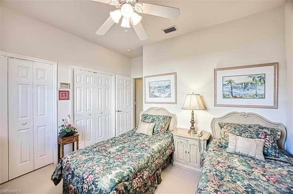 Bedroom with multiple closets, ceiling fan, and light carpet