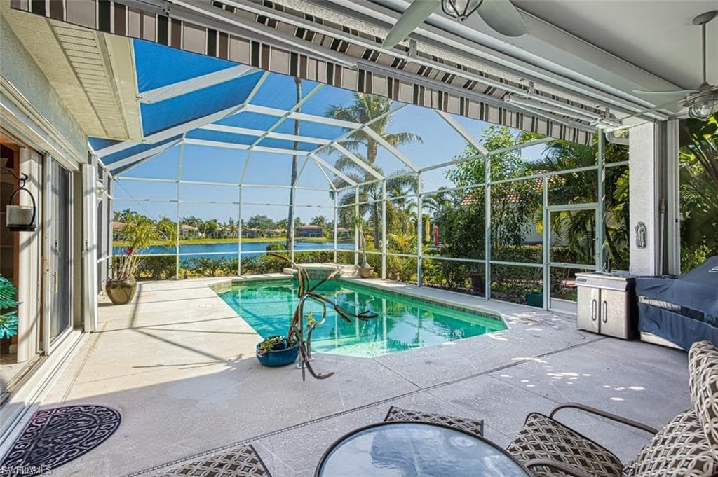 Swimming pool with a patio area, a sunroom, a water view, and glass enclosure