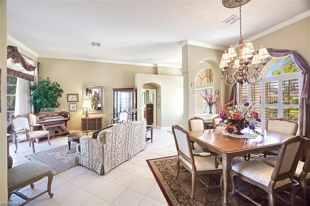 Dining area with arched walkways, crown molding, light tile patterned flooring, and a chandelier
