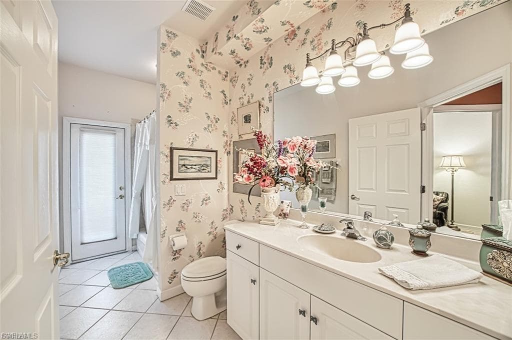 Full bath featuring vanity, light tile patterned floors, shower / bathtub combination with curtain, and wallpapered walls