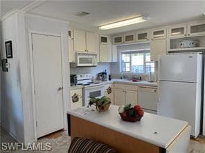 Kitchen featuring glass insert cabinets, white appliances, light countertops, and white cabinetry