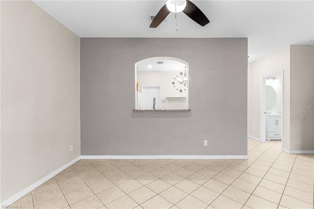 Empty room with light tile patterned floors and a ceiling fan