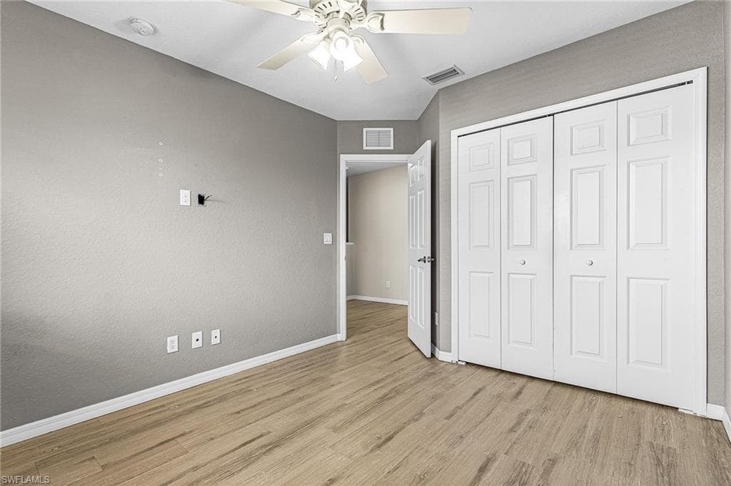Unfurnished bedroom featuring light wood finished floors, a closet, and a ceiling fan