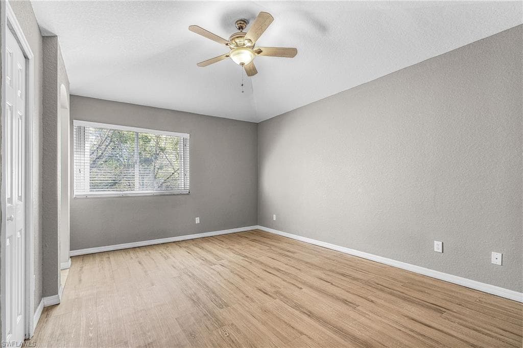 Unfurnished bedroom featuring light wood-style floors, a ceiling fan, a textured wall, and a closet