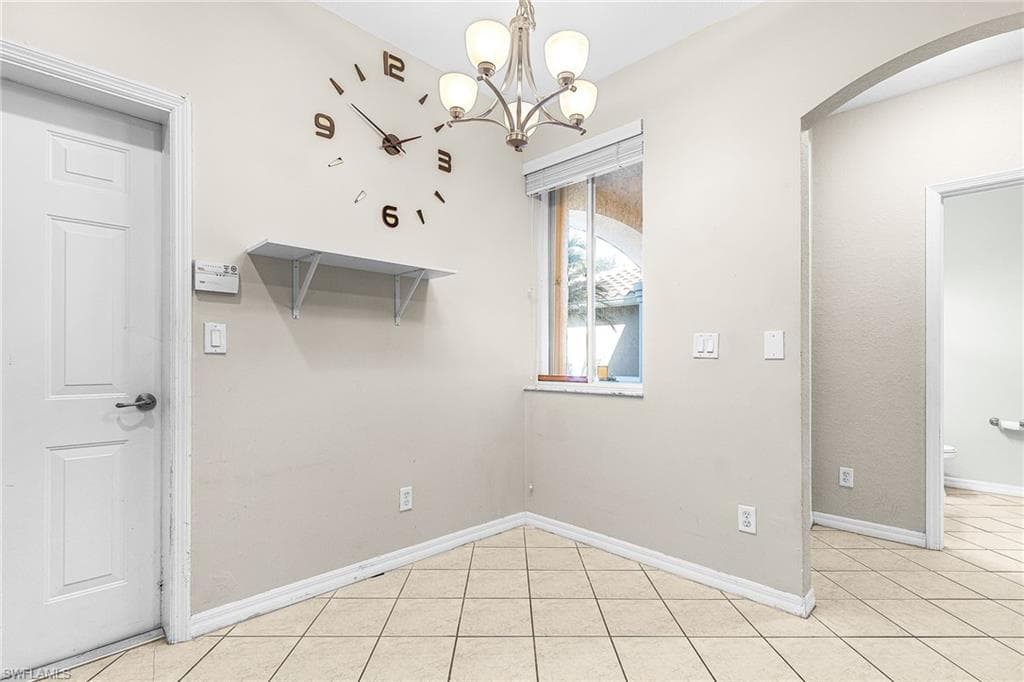 Unfurnished dining area featuring light tile patterned floors, a chandelier, and arched walkways