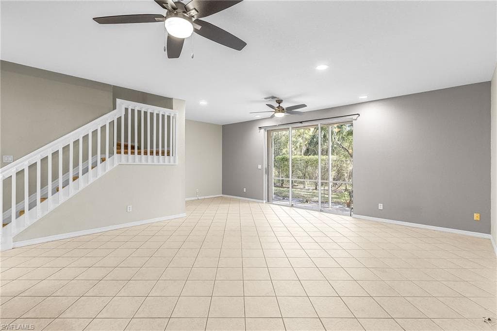 Unfurnished living room featuring recessed lighting, ceiling fan, and stairway