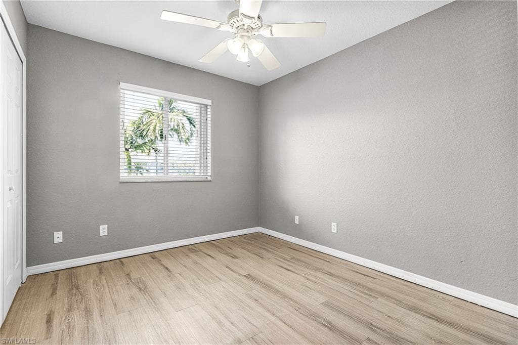Spare room featuring light wood-style floors, ceiling fan, and a textured wall