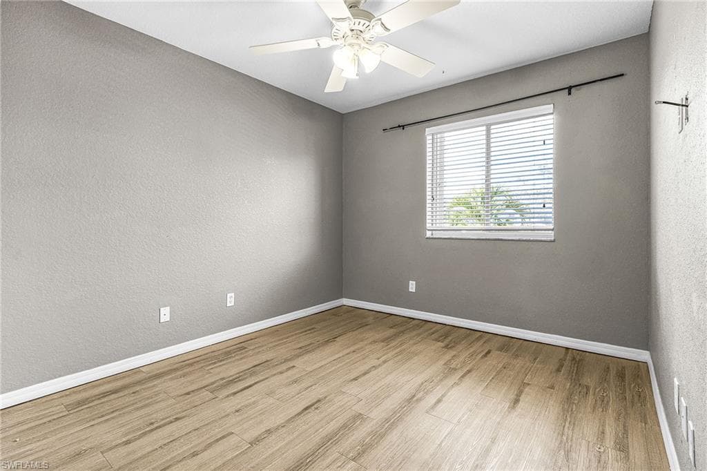 Spare room featuring a textured wall, light wood-style flooring, and ceiling fan