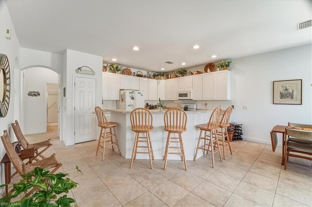 VIRTUALLY STAGED Open-concept living area featuring high ceilings, a second-story interior balcony with white balusters and wood handrail, arched doorways, a carpeted floor, and a double-door entry