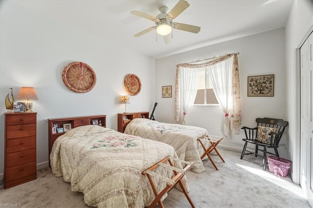 Carpeted bedroom with a tray ceiling and a ceiling fan