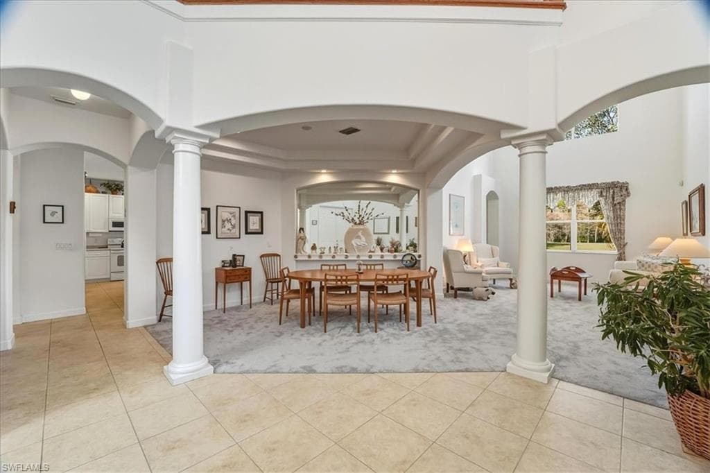 Kitchen featuring white appliances, a breakfast bar area, white cabinetry, recessed lighting, and light tile patterned flooring