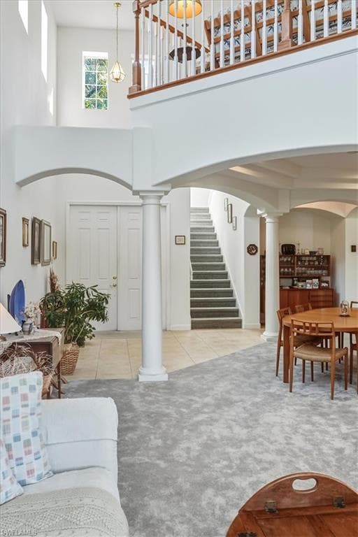Dining space featuring decorative columns, light carpet, recessed lighting, a raised ceiling, and arched walkways