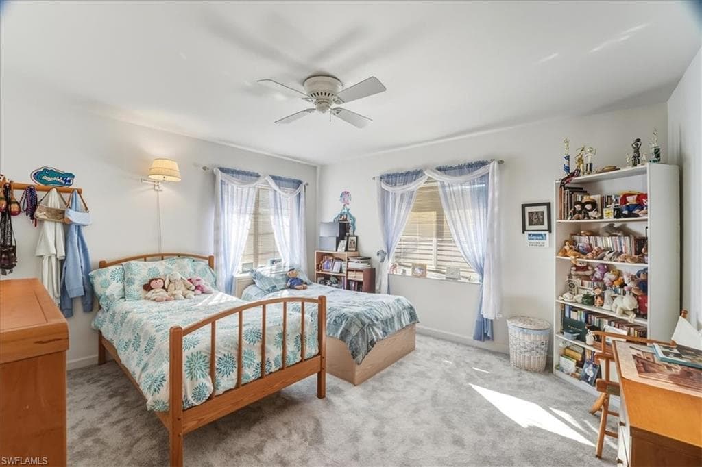 Living area with light colored carpet, track lighting, and a ceiling fan