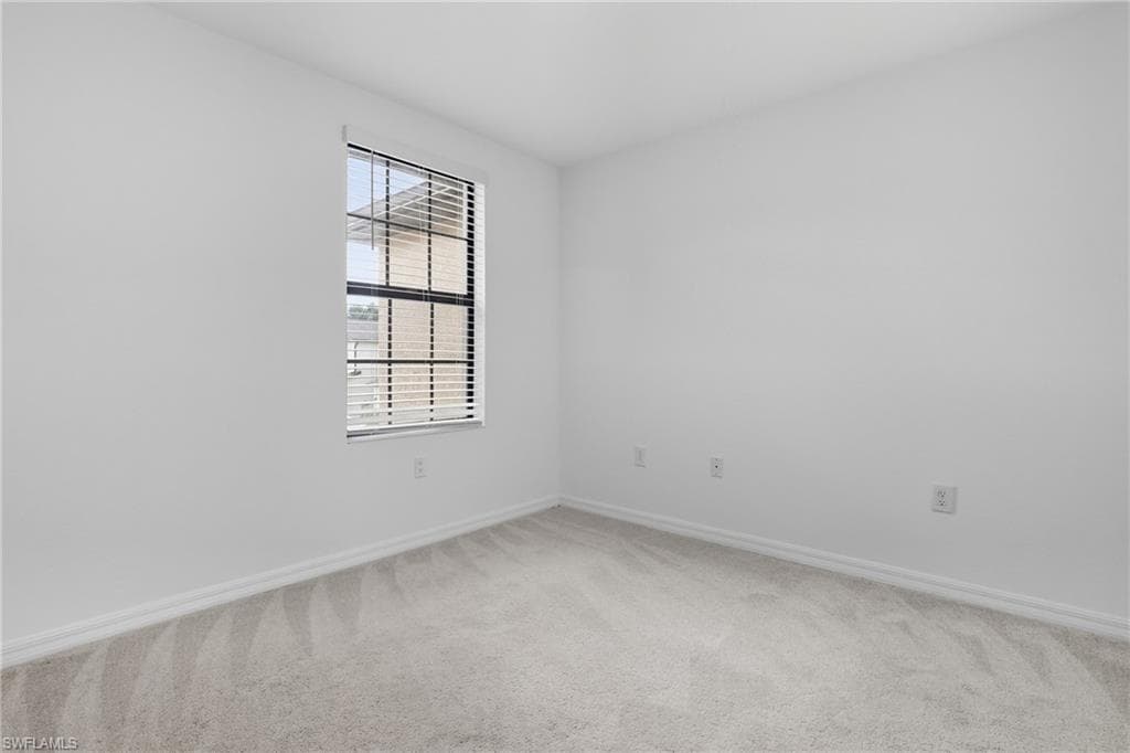 Unfurnished room with baseboards and light carpet