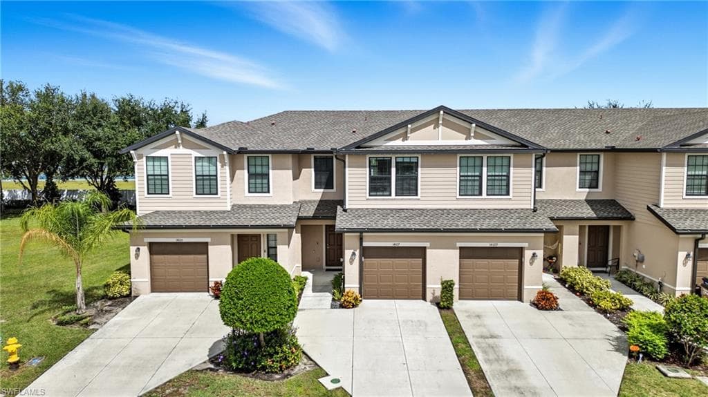 View of front of house featuring driveway, roof with shingles, a garage, and a front lawn