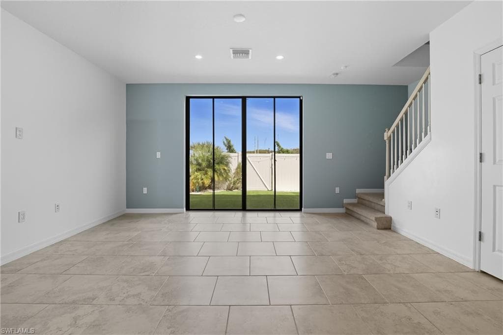 Unfurnished living room featuring stairs and recessed lighting