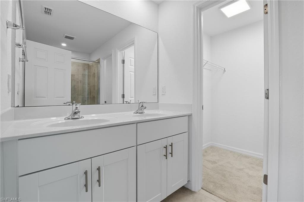 Full bath featuring a shower stall, double vanity, and light colored carpet