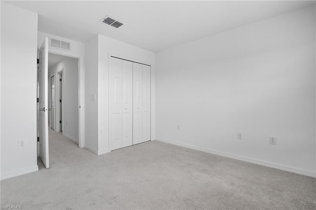 Unfurnished bedroom with light carpet and a closet