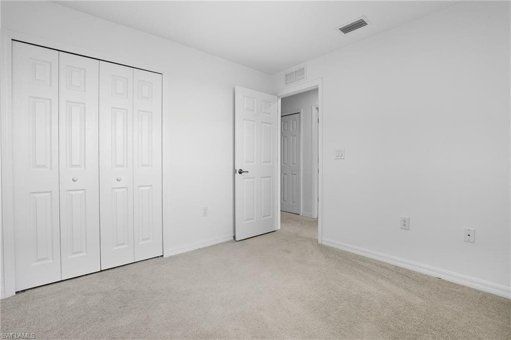 Unfurnished bedroom featuring light carpet and a closet