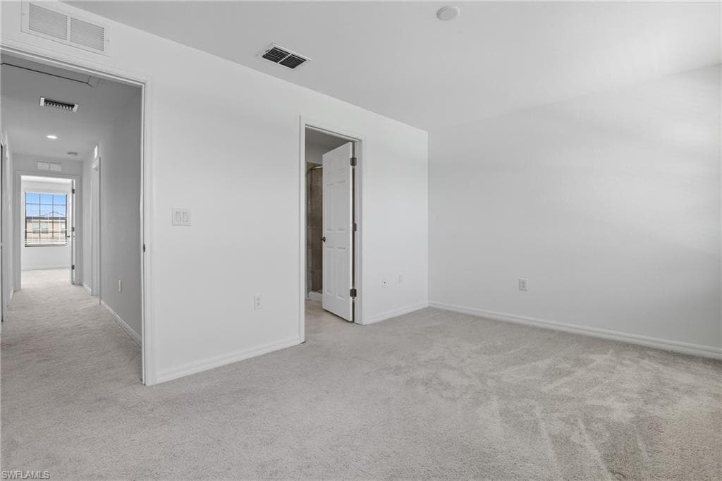 Empty room featuring light colored carpet and baseboards