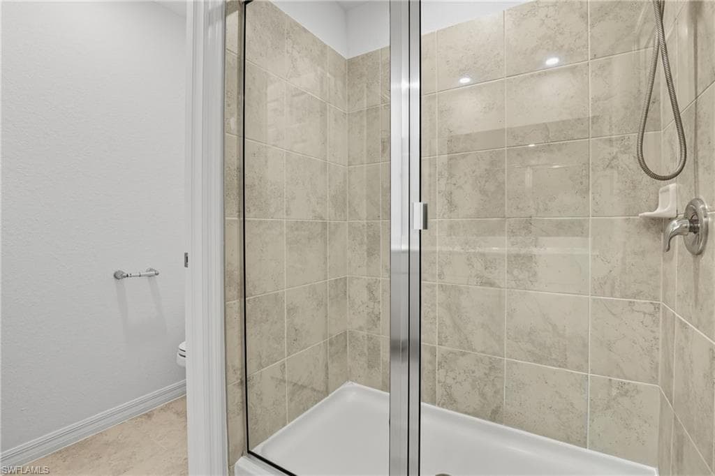 Full bath with a shower stall and baseboards