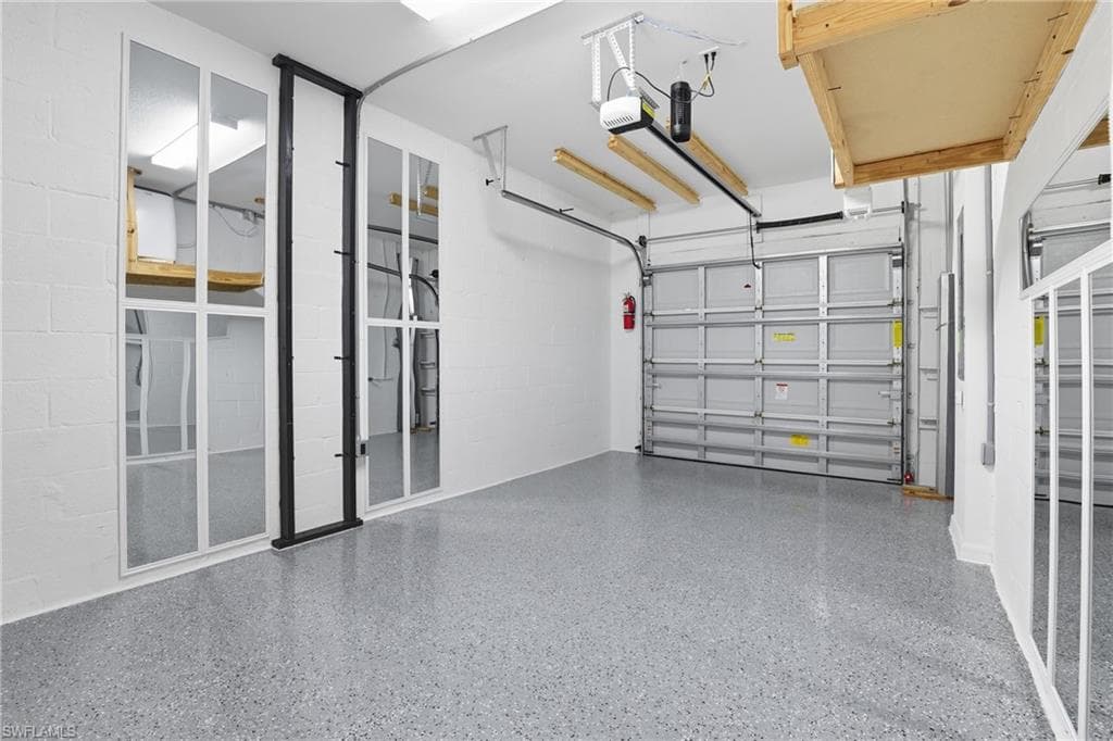 Garage featuring concrete block wall and a garage door opener