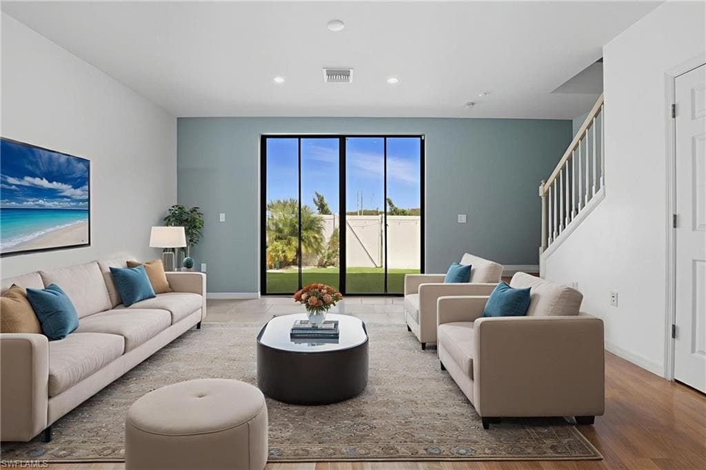 Living room with recessed lighting, wood finished floors, and stairs