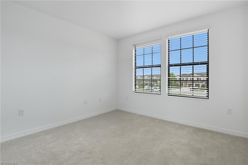 Empty room with light carpet and baseboards
