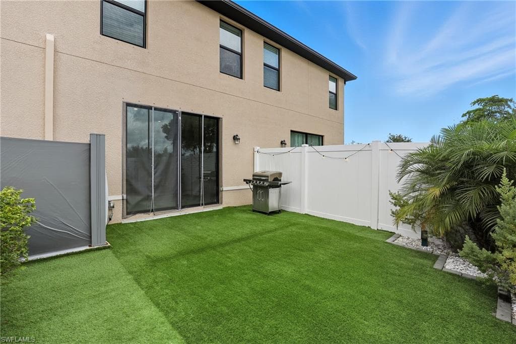 Rear view of house featuring a fenced backyard and stucco siding