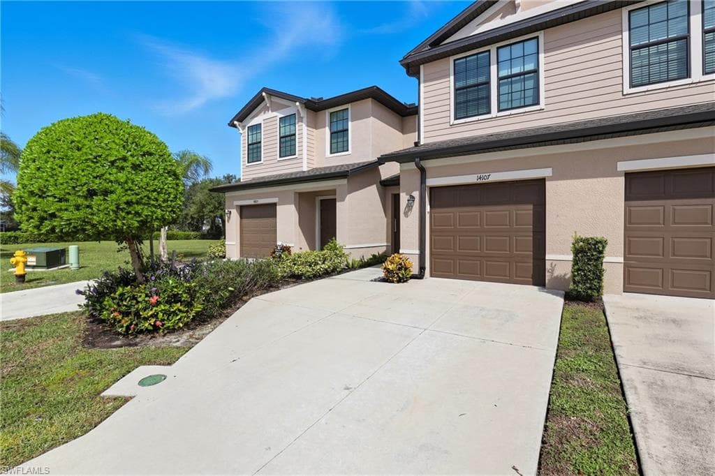View of front facade with driveway, stucco siding, and an attached garage