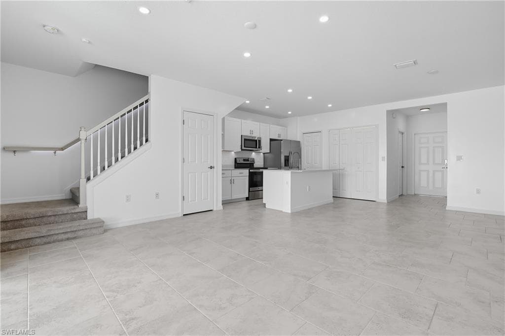 Unfurnished living room featuring recessed lighting and stairway