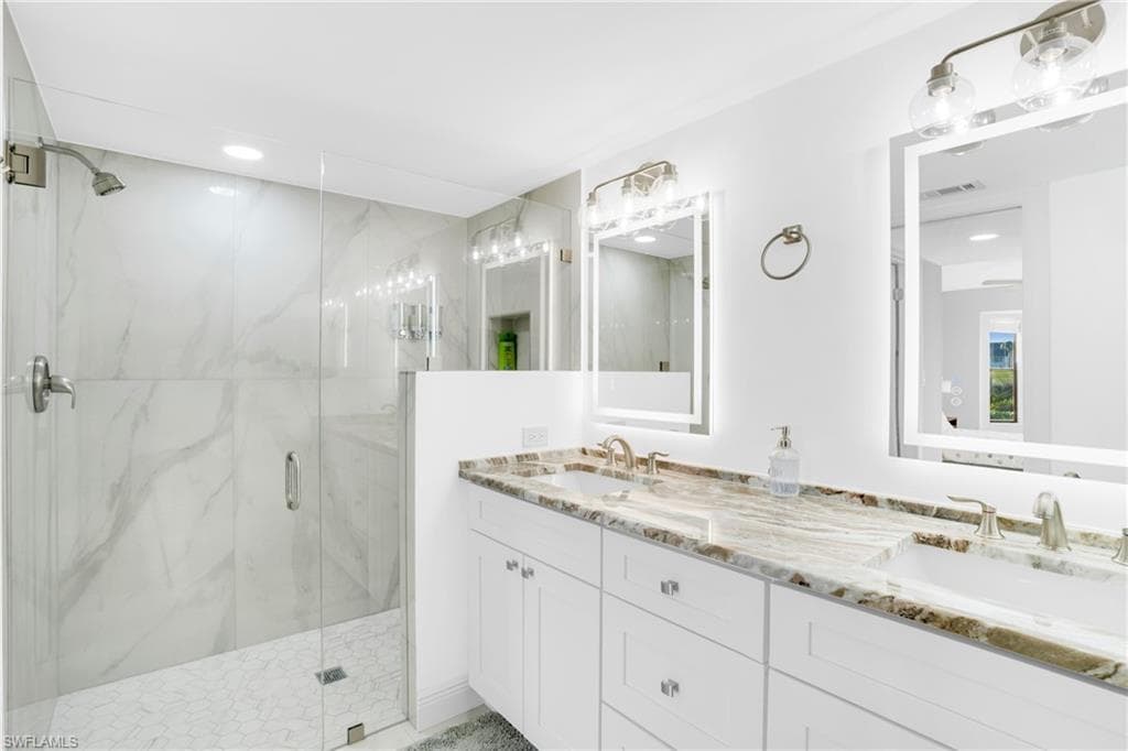 Bathroom featuring double vanity, a marble finish shower, and recessed lighting