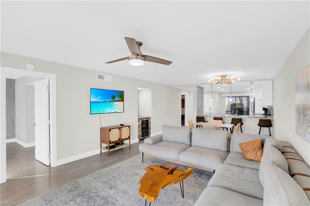 Living area featuring wood finish floors, a chandelier, ceiling fan, and beverage cooler