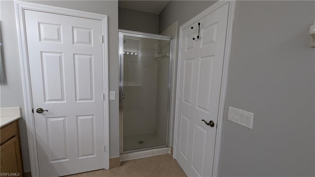 Full bath featuring light tile patterned floors, vanity, and a stall shower