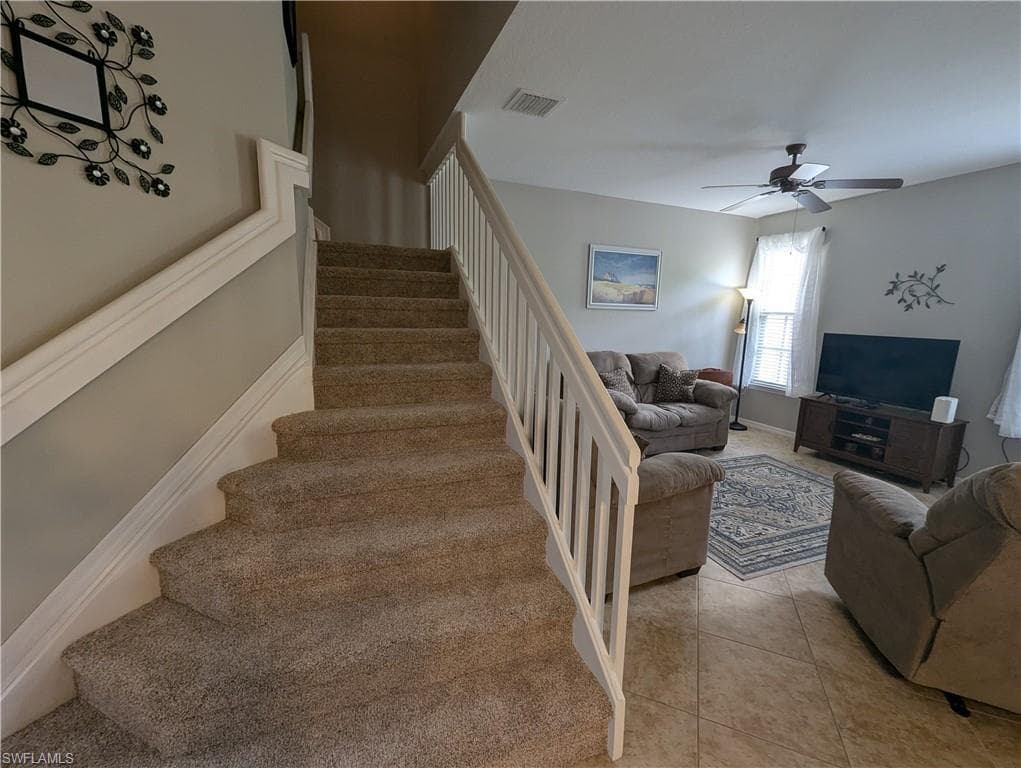 Staircase with tile patterned flooring and ceiling fan