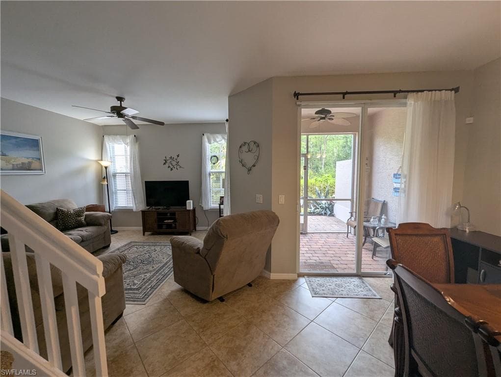 Tiled living room featuring a ceiling fan and baseboards