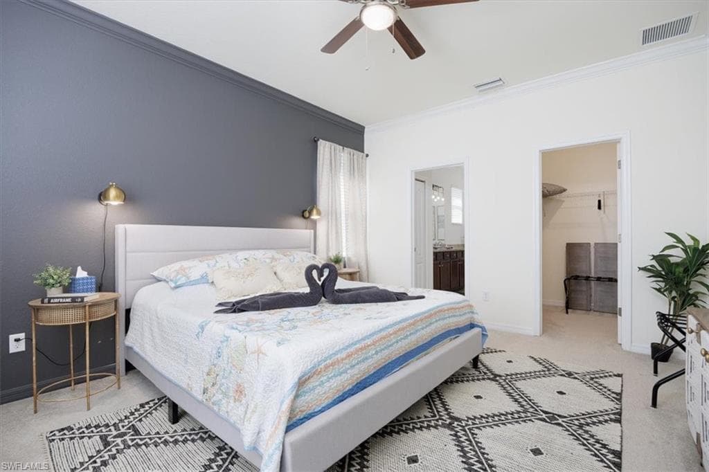 Owners Bedroom featuring light colored carpet, crown molding, ceiling fan, a spacious closet, and ensuite bathroom